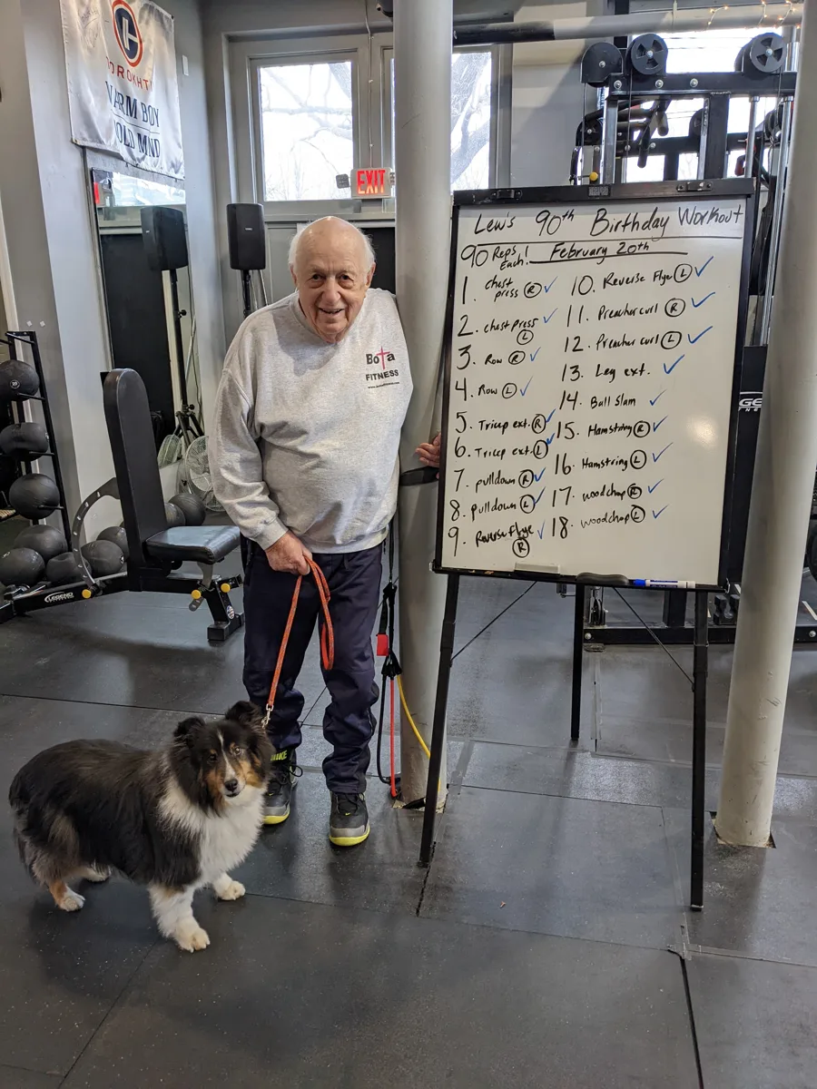 Lew with his dog next to the whiteboard for his 90th birthday workout