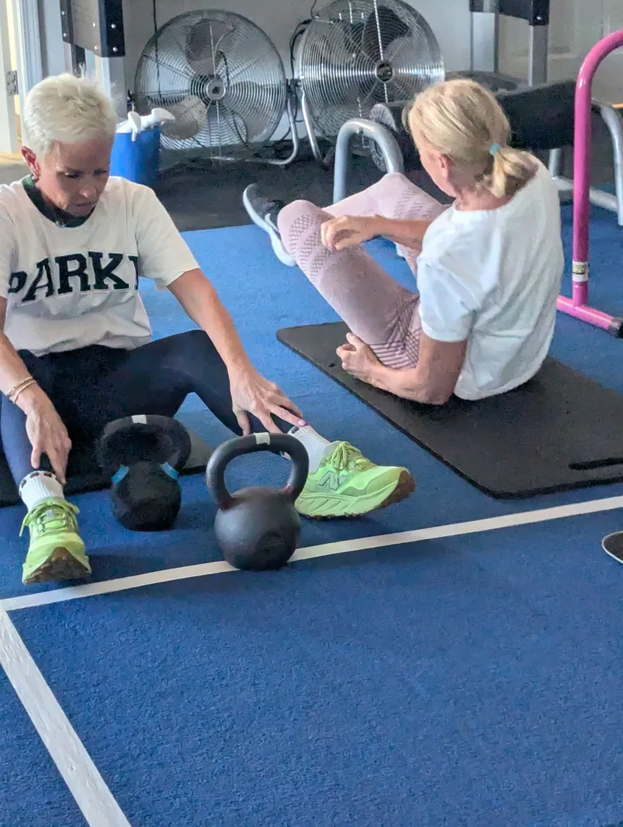 An older member doing a seated core exercise with a coach at Next Level Gym