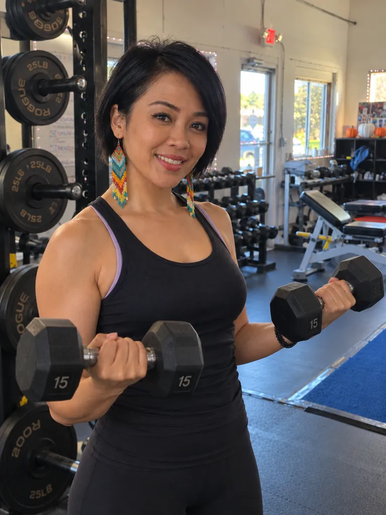 Coach Ruth curling dumbbells at Next Level Gym