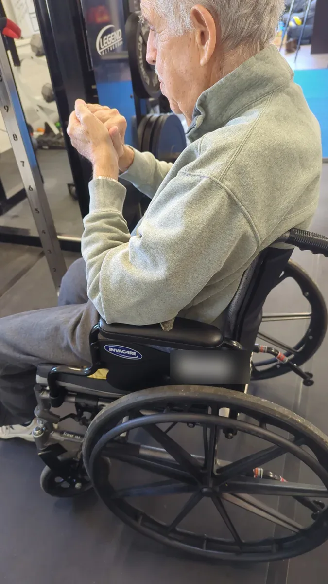 An older member in a wheelchair doing a cable exercise at Next Level Gym